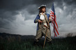 © Fotokvadrat - Man in United States War of Independence soldier costume with flag posing in forest. 4 july independence day of USA concept photo composition