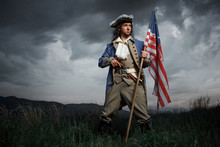 Man In United States War Of Independence Soldier Costume With Flag Posing In Forest. 4 July Independence Day Of USA Concept Photo Composition
