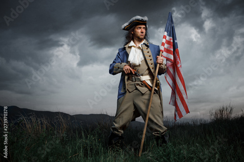 Cuadros en Lienzo Man in United States War of Independence soldier costume with flag posing in forest