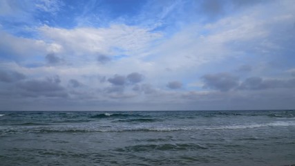 Wall Mural - Timelapse shot from the Mediterranean. The waves are coming at a normal pace. The clouds in the sky pass very fast. Time June.