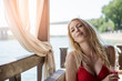 Young beautiful blonde girl sits in the summer cafe pavilion outdoors and holds a glass of