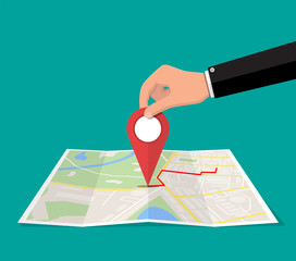 Poster - Location pin in hand and paper map. City map with houses, parks, streets and roads. City aerial view. GPS, navigation and cartography. Vector illustration in flat style