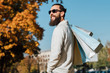 © golubovy - Man fashion style. Bearded hipster guy with shopping bags enjoying autumn sunny day. Blur fall trees and blue sky background.