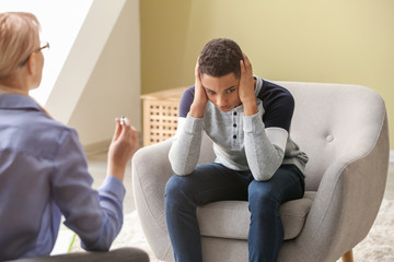 Poster - female psychologist working with depressed teenage boy in office