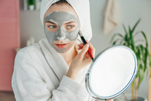 Young Woman Applying Clay Mask At Home