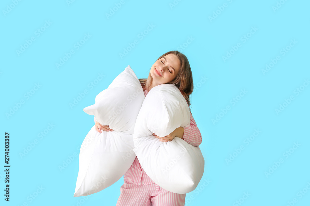 Young woman with pillows on color background