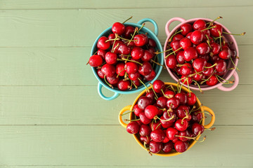 Pots with sweet ripe cherry on wooden background