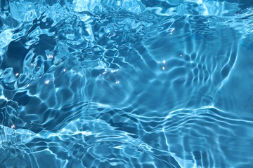 blue and bright water surface with sun refection in swimming pool for background