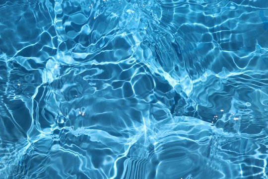 blue and bright water surface with sun refection in swimming pool for background