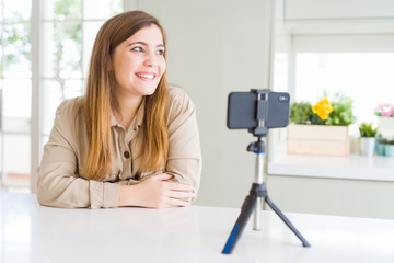 Canvas Print - Beautiful young woman doing online video call using smartphone webcam looking away to side with smile on face, natural expression. Laughing confident.