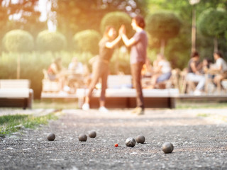 Wall Mural - Happy couple playing petanque in city park on a sunset