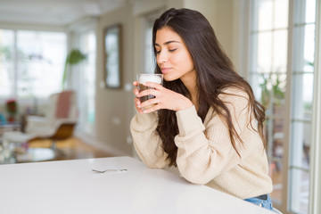 Wall Mural - Beautiful young girl drinking a cup of coffee at home and smiling