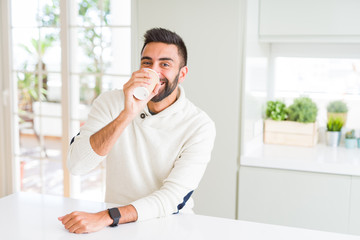 Wall Mural - Handsome man smiling while enjoying drinking a take away coffee in the morning