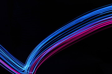 Wall Mural - Long exposure, light painting photography.  Vibrant electric blue and neon pink streaks of colour against a black background