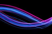 Long Exposure, Light Painting Photography.  Vibrant Electric Blue And Neon Pink Streaks Of Colour Against A Black Background