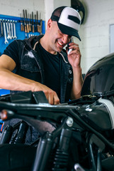 Wall Mural - Mechanic talking on the phone while fixing the motorbike