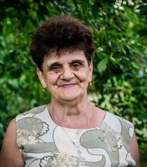 Elderly caucasian woman on a background of green summer garden