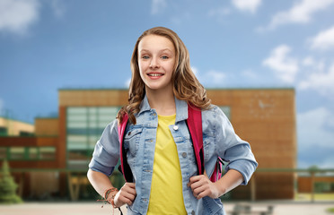 Poster - education and people concept - happy smiling teenage student girl with bag over school background