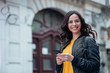 © bnenin - Portrait of a girl walking in the town street, holding smart phone and smiling at camera.