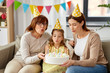 © Syda Productions - family, generation and celebration concept - smiling mother, daughter and grandmother in party hats blowing candles out on birthday cake at home
