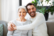 Family, Generation And People Concept - Happy Smiling Senior Mother With Adult Son Hugging At Home