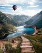 River in Austria alps. Vertical Wallpaper. With stairs leading down to a river and a balloon flying in the air. Partially cloudy day
