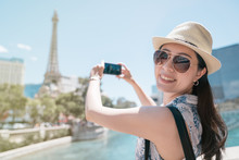 Cheerful Asian Female Tourist In Sunglasses Taking Photo Of Eiffel Tower In Paris With Smartphone. Young Smiling Girl Backpacker In Straw Hat Looking In Camera. Happy Woman Travel In Europe In Summer