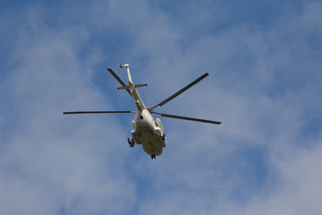 Helicopter flies against a blue sky background. Transport