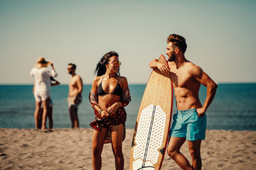 Young man and woman with a surf board on the beach