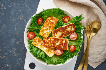 Wall Mural - Vegan salad with fried halloumi and tomatoes, dark background, top view