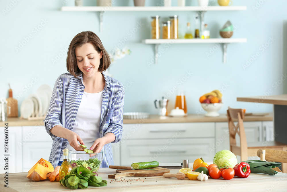Young woman making salad in kitchen