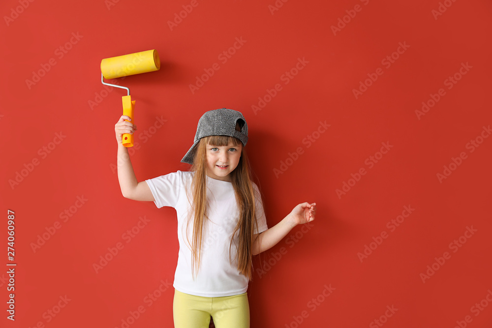 Cute little girl with paint roller on color background