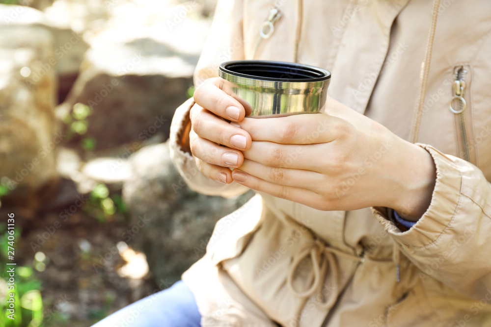 Female tourist drinking tea in forest, closeup