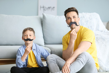 Sticker - Portrait of funny father and son with fake mustache at home