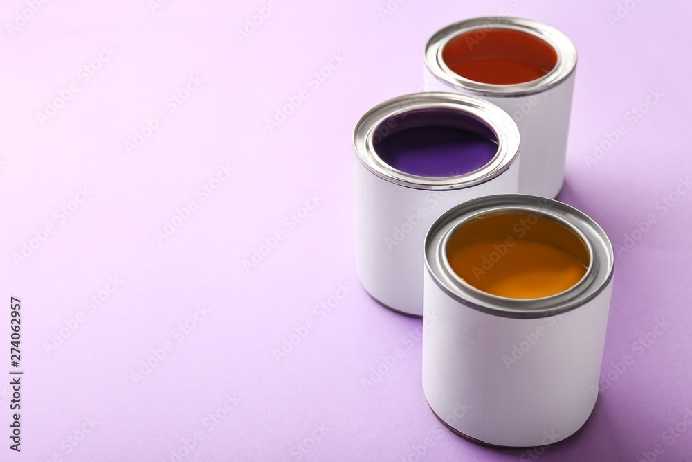 Cans of paint on color background