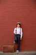 © Tomsickova - Cute child, boy in vintage cloths, eating lollipop ice cream, sitting on vintage suitcase in front of a red brick wall