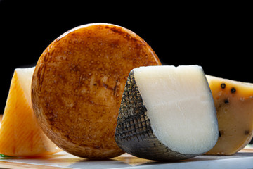 Variety of Italian pecorino cheeses, yellow aged, with black peppers from Nebrodi, white Il Palio and black molarotto, close up