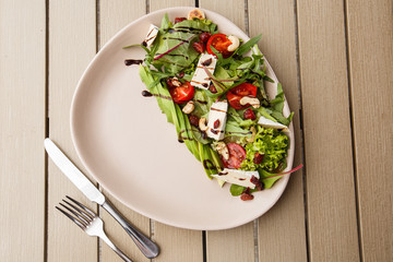 Tasty and healthy salad with arugula, brie, cheese, avocado, cherry tomatoes, dry cranberry and cashews. Top view. The flat lay. Banner