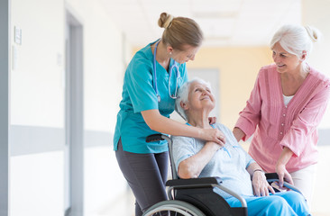 Elderly woman on wheelchair with her daughter and nurse