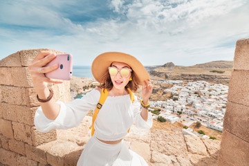 Wall Mural - Happy young woman taking selfie at the observation point of ancient landmark