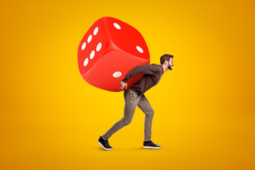 Poster - young man in casual clothes carrying big red casino dice on his back on yellow background