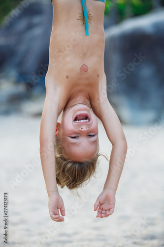Cuadros en Lienzo boy 5 years old hanging upside down on the beach