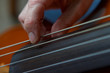 Caucasian womans hand plucking cello strings close up