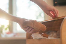 Woman Taking A Bread Loaf From A Bread Box In The Kitchen At Home