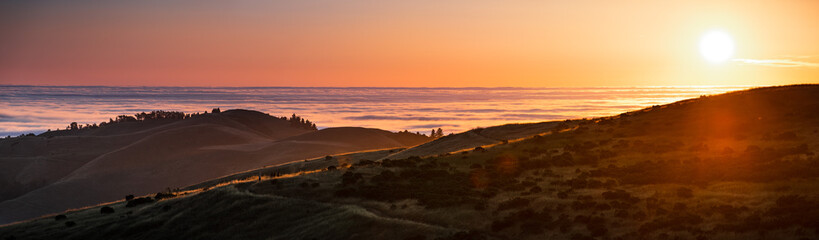 Wall Mural - Panoramic view at sunset of valley covered in a sea of clouds in the Santa Cruz mountains, San Francisco bay area, California