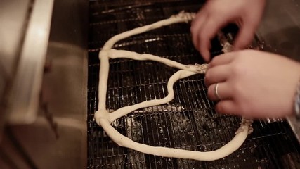 Wall Mural - Woman making fresh pretzels with sunflower and sesame seeds in the bakery. Baking buns on the production line in the baking industry