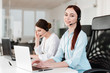 © Anastasia - Smiling young office worker with a headset  answering in a call center, woman talking with clients. Portrait of an attractive customer and technical support representative. Business concept