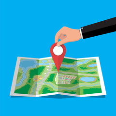 Poster - Location pin in hand and paper map. City map with houses, parks, streets and roads. City aerial view. GPS, navigation and cartography. Vector illustration in flat style