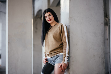 Mature female amputee personal trainer in crop top posing with confidence with prosthetic limb and foot against a wall hands on hips in power. Portrait. Inspiration for memes overcoming adversity