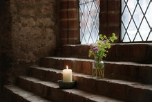 Flower Vase And A Burning Candle On Brick Steps As Decoration At A Lead Glass Window In An Old Monastery, Copy Space